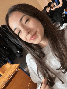 a girl taking a selfie in a room with a group of people