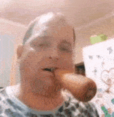 a man is eating a carrot in front of a refrigerator .