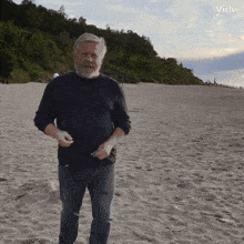 a man with a beard is standing on a sandy beach with vidu written on the bottom right