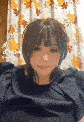 a woman 's face is shown in front of a floral curtain with tiktok written on it