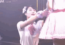 a girl with a flower in her hair is standing next to a girl in a pink skirt .