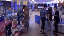 a group of people are standing around a stack of boxes in a living room .