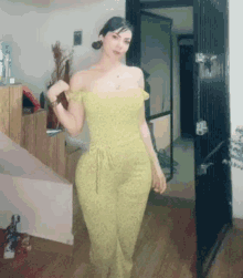 a woman in a yellow jumpsuit is standing in a room