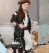 a blurry picture of a woman wearing a hat and a jacket standing next to a dog .