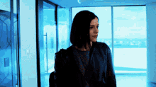 a woman in a black leather jacket is standing in a hallway