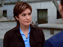 a woman wearing a plaid jacket and a blue shirt is talking to a man
