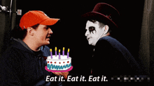a man is holding a cake with candles on it and says eat it