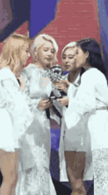 a group of women in white dresses are standing next to each other on a stage .