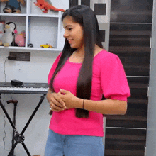 a woman in a pink shirt is standing in front of a piano keyboard