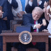 the president of the united states is sitting at a desk with a hammer in his hand