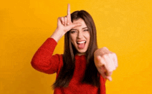 a woman in a red sweater is making a funny face and pointing at the camera with her finger .