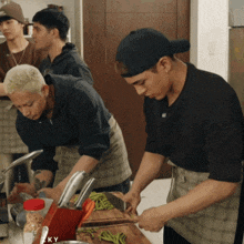 a group of young men are preparing food in a kitchen with a knife block that says ' ky ' on it