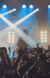 a crowd of people at a concert with their hands up in the air