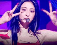 a woman with a microphone in her mouth is making a peace sign