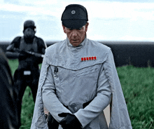 a man in a star wars uniform stands in a field with his arms folded