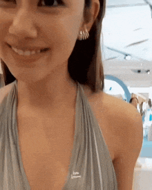 a close up of a woman wearing a gray dress and earrings