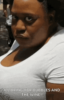 a woman in a white shirt is making a funny face and says i 'll bring ybr bubbles and the wine