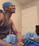 a man wearing a blue bandana and a black tank top