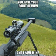 a sniper rifle with a scope is sitting on top of a grass covered hill .