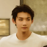 a close up of a young man 's face with a white shirt on