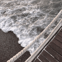 a rope runs along the edge of a wooden dock near the ocean