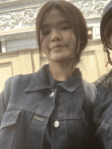 a woman wearing a denim jacket and a black helmet smiles for the camera