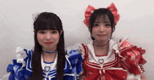 two girls are standing next to each other wearing blue and red dresses