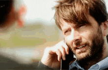 a man with a beard is talking on a cellphone .