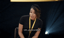 a woman wearing a black shirt and a yellow lanyard says um you 're a bitch