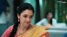 a woman wearing a yellow and pink saree with a blushyanu logo on the bottom right
