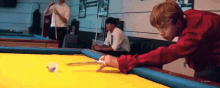 a man in a red shirt is playing pool on a pool table