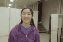 a girl wearing a purple hoodie and a purple shirt smiles