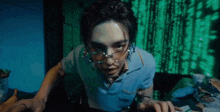 a man wearing glasses and earrings is standing in front of a green screen .