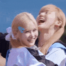 two blonde girls are laughing and hugging each other .