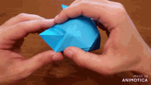 a person is holding a piece of blue paper and the words made in animotica can be seen behind them