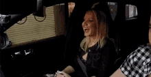 a woman is laughing while sitting in the back seat of a car with a man .