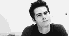 a black and white photo of a young man in a black shirt making a funny face .