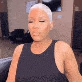 a woman with a very short white haircut is sitting in a chair .