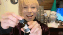 a man with blonde hair is holding a small bottle with a label that says ' s ' on it