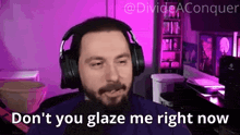 a man with a beard wearing headphones is sitting in front of a microphone in a purple room .