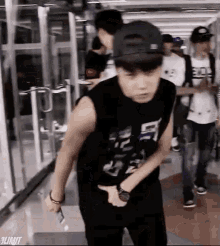 a young man wearing a baseball cap and a sleeveless shirt is standing in a subway station .