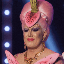 a drag queen wearing a pink dress and a pink flower in her hair