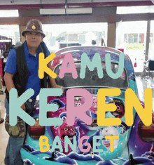 a man stands in front of a colorful car that says kamu keren banget