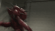 a man in a robot costume is fighting a red monster in a dark room .