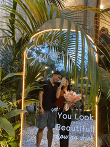 a man and woman taking a picture in front of a mirror that says hey you look beautiful
