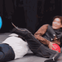 two men are playing with a ball on the floor and one of them is kicking the other .