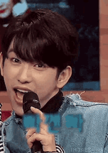 a young man is holding a microphone in his hand and making a funny face .
