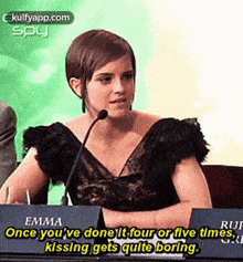 emma watson is sitting at a table with a microphone in front of her .