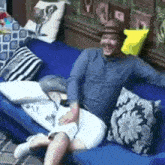 a man in a hat is sitting on a blue couch