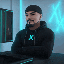 a man with a beard wears a black hoodie with the letter x on the front